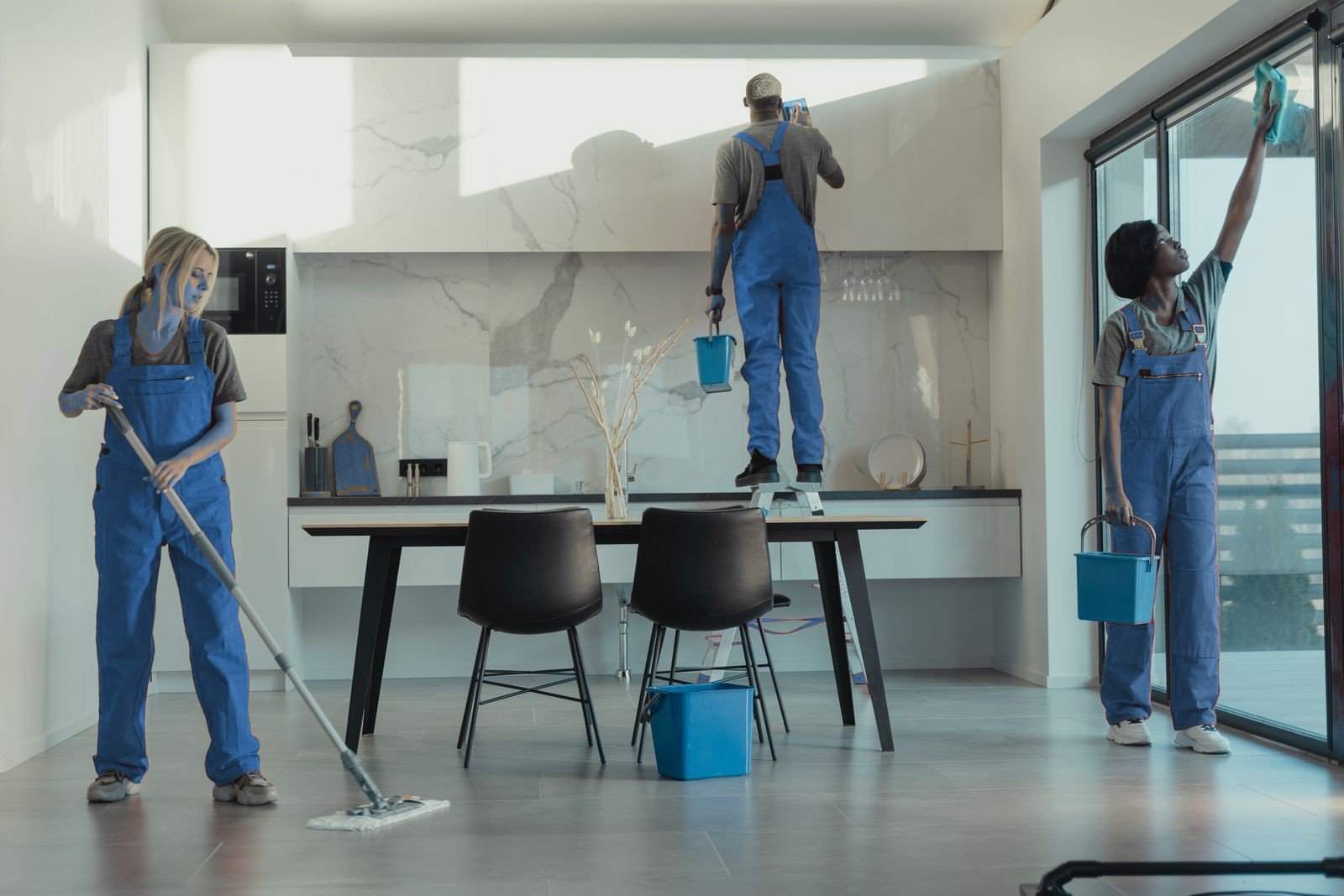 Cleaning team mopping, wiping surfaces and tidying a modern kitchen